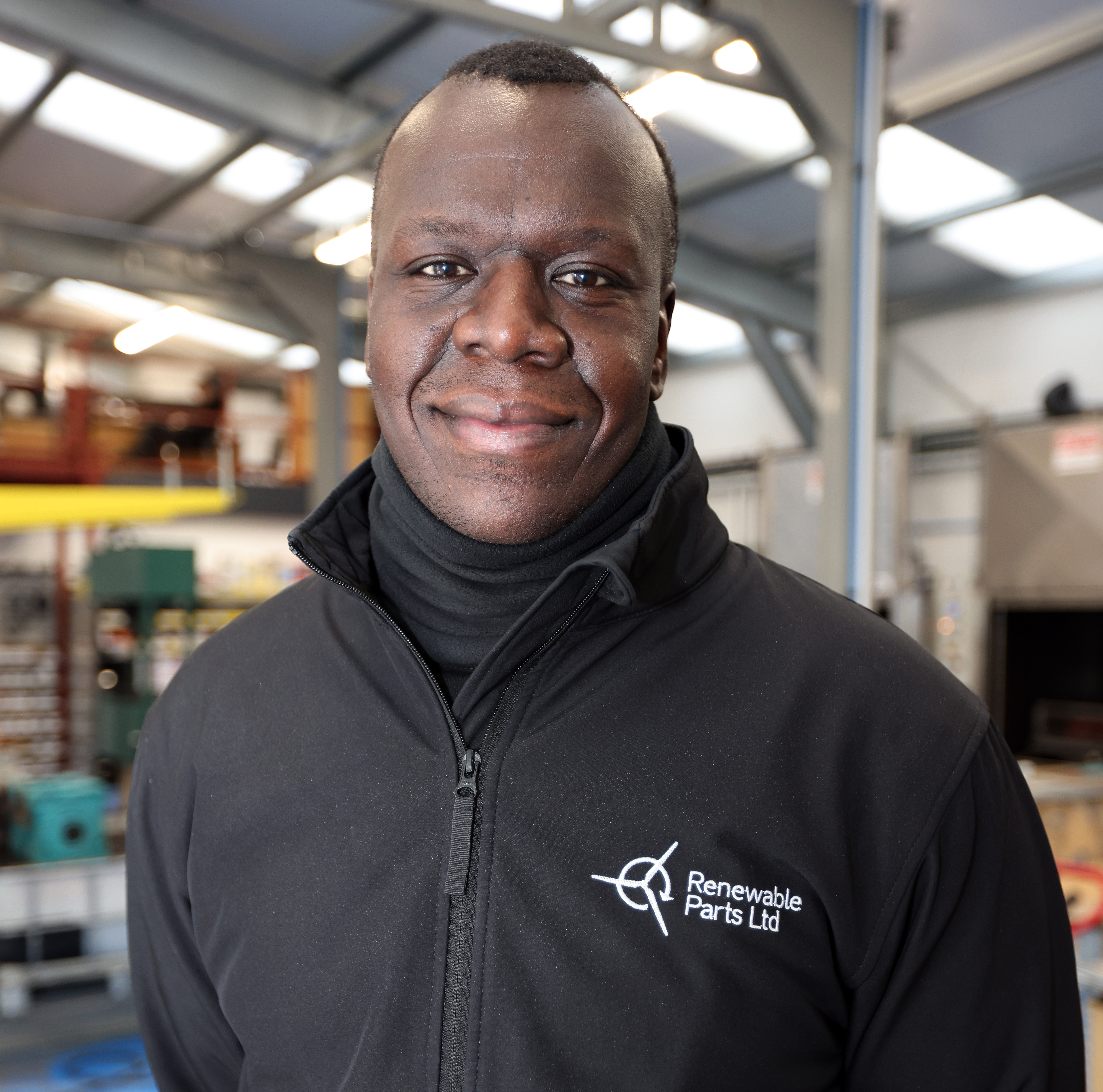 Picture of man smiling in a factory wearing Renewable Parts Ltd jacket