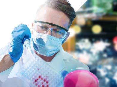 Man in lab coat with mask and goggles using a beaker and dropper