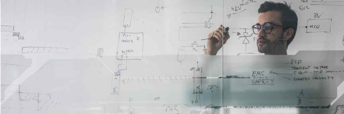 Photo of engineer doing equations on a whiteboard.