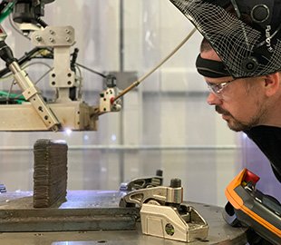 Man in safety goggles looking closely at metal making machine