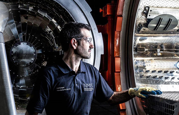 Man in polo shirt and safety goggles looking into a circular machine opening